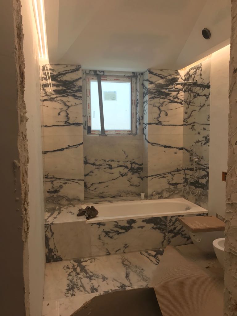 Casa de banho revestida em mármore Calacatta Viola com banheira